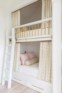 there is a bunk bed with curtains and pillows on the bottom level, next to a ladder