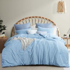 a bed with blue comforters and pillows in a room next to a wicker headboard