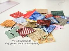 a pile of small pieces of fabric sitting on top of a white table next to a cup