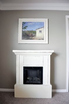 a white fireplace with a painting on the wall above it