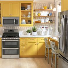 a kitchen with yellow cabinets and stainless steel appliances