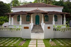 a white house with green doors and steps leading up to it