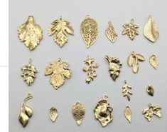 several different types of gold leaf pendants on a white surface, including one with an acorn and the other with leaves