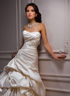 a woman in a wedding dress leaning against a wall