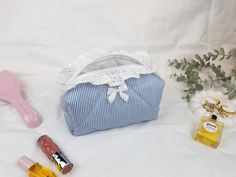 This beautifully handcrafted makeup bag is perfect for organizing your beauty essentials. Featuring a classic blue and white striped cotton fabric, adorned with delicate lace trim and a satin bow, it adds a touch of elegance to your everyday routine. The bag is fully lined and closes with a secure zipper, making it ideal for both travel and daily use. Its compact size fits easily in your handbag or suitcase, and it can also be used to store small accessories. Add a stylish and functional piece to your beauty routine with this elegant, handmade cosmetic pouch! Size: Mini Size: 13 cm x 10 cm x 7 cm (5.1" x 3.9" x 2.7") Medium Size: 18 cm x 10 cm x 8 cm (7.0" x 3.9" x 3.1") Large Size: 22 cm x 12 cm x 10 cm (8.6" x 4.7" x 3.9") X-Large (Travel) Size: 29 cm x 15 cm x 12 cm (11.4" x 5.9" x 4.7" Cute Small Makeup Bags, Blue Makeup Bag, Handmade Makeup Bag, Stylish Makeup, Handmade Cosmetics, Everyday Routine, Bag With Zipper, Blue Makeup, Toiletry Storage