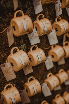 several coffee cups hanging on a wall with tags attached to it's sides,