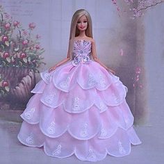 a barbie doll wearing a pink dress with white flowers on the wall in front of it