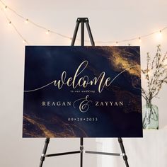 a welcome sign is displayed on an easel in front of a string of lights