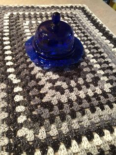 a blue glass covered dish sitting on top of a black and white tableclothed place mat