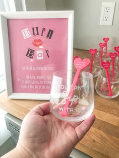 a person holding up a wine glass in front of a framed photo and other items