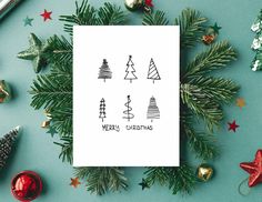 a card with christmas trees on it next to other holiday decorations and gifts around it