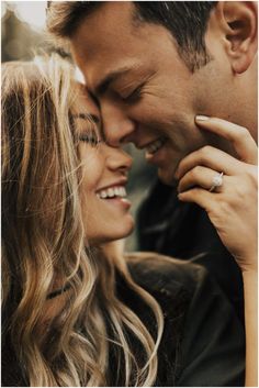 a man and woman kissing each other while holding their hands close to the foreheads