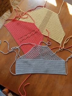 three knitted masks sitting on top of a wooden table next to yarn and twine