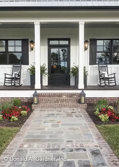 front porch with rocking chairs and flowers on the side walk leading to the front door