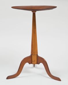 an old wooden table with two legs and a small round top on one end,