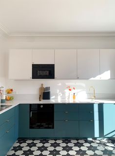 a kitchen with black and white flooring, blue cabinets and an oven on the wall