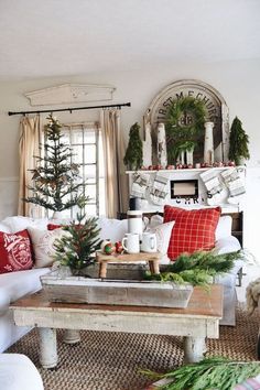 a living room decorated for christmas with white furniture and red pillows on the couches