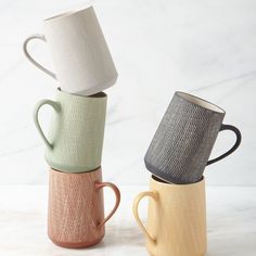 three different colored coffee mugs stacked on top of each other in front of a white background