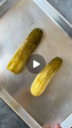 two pickles sitting on top of a metal pan