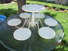 a glass table with six plates on it in the grass next to a tree and fence