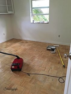 an empty room with hard wood floors and a vacuum