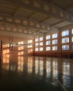 an empty tennis court with sun shining through the windows