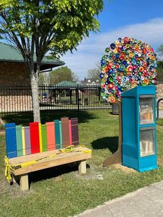 two colorful benches sitting in the grass next to a tree with buttons on it's top