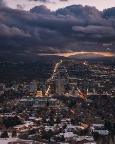 an aerial view of a city at night with dark clouds in the sky and snow on the ground