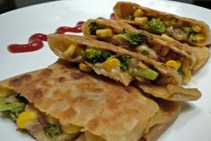 two quesadillas with broccoli, corn and ketchup on a white plate