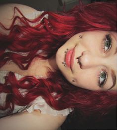 a woman with red hair and piercings on her face