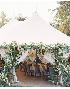 a white tent with tables and chairs covered in greenery