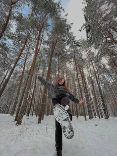 a snowboarder is doing a trick in the middle of a snowy forest area