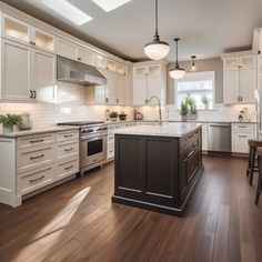 a large kitchen with white cabinets and wood flooring, along with an island in the middle