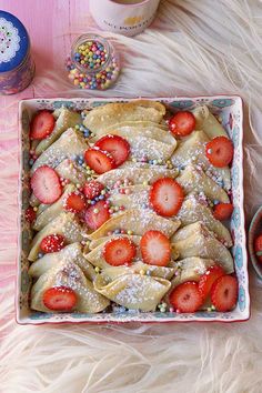 a dessert with strawberries and sprinkles in a blue dish on a pink tablecloth