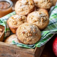 some muffins are in a wooden box on a table next to an apple