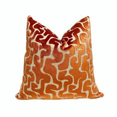 an orange and white pillow with wavy lines on the front, sitting on a white surface