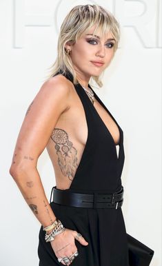 a woman with tattoos on her back posing for the camera and wearing a black dress