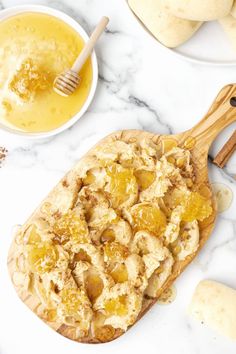 a wooden spoon sitting on top of a white counter next to some fruit and bread