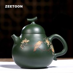 a green tea pot with a bird painted on it