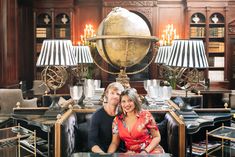 a man and woman sitting on a couch in front of a table with two lamps