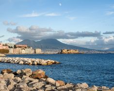 a body of water with rocks in front of it and buildings on the other side