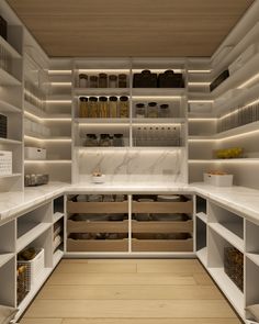 an organized pantry with white shelving and wooden floors