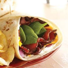 a burrito filled with meat and vegetables on a red plate next to some fries