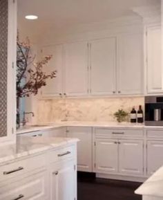 a kitchen with white cabinets and marble counter tops