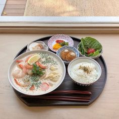 a plate with rice, shrimp and vegetables on it next to chopsticks in front of a window