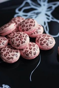 pink and black decorated cookies sitting on top of a table