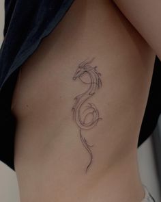 a woman's stomach with a tattoo design on the side and an outline of a dragon