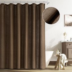 a bathroom with a brown shower curtain next to a white bath tub and wooden floors