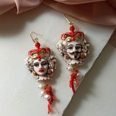 Baroque style earrings made of: - Sicilian handpainted Ceramic heads; - Red Natural Coral branches; - Gold plated 925 Sterling Silver hooks. Lenght : 7,5 cm / 2,96 inches * SHIPPING * Your order will be shipped within 1-3 business days from your purchase. You can choose between 2 shipping methods: STANDARD MAIL (NOT TRACEABLE) It is a cheap and fast shipping method, but NOT TRACEABLE. Chapeau Atelier is not responsible for any postal disruptions, delays or losses. REGISTERED MAIL (TRACEABLE) It Ornate Red Dangle Earrings, Red Chandelier Earrings As Gift, Red Hand Painted Earrings For Gift, Ornate Red Earrings For Party, Elegant Red Hand Painted Jewelry, Elegant Hand Painted Jewelry For Party, Artistic Red Earrings For Gifts, Baroque Pierced Earrings As Gift, Red Hand-painted Dangle Jewelry