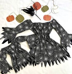 an intricately designed piece of clothing and decorations on a white sheet with pumpkins in the background